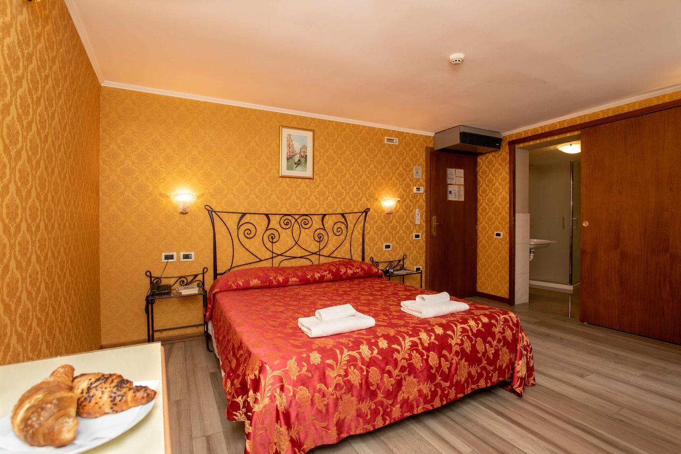Camera dell'Hotel Tintoretto con tessuti rossi e pareti damascate