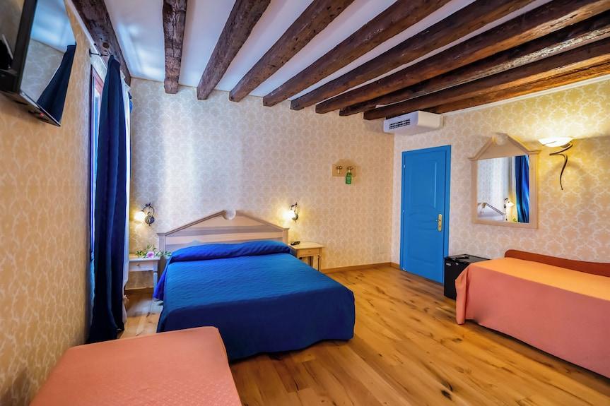 Camera dell'Hotel Tintoretto con travi a vista e copriletto blu